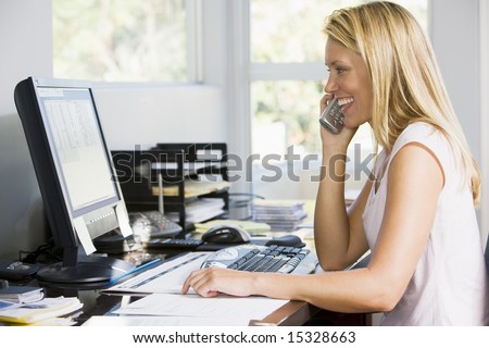 Woman in home office with computer using telephone smiling