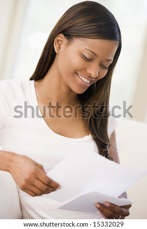 Woman in living room reading papers smiling