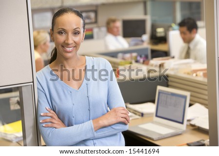 Businesswoman standing in cubicle smiling