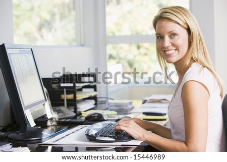 Woman in home office with computer smiling