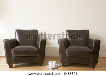 Two chairs with coffee mug and magazines between them