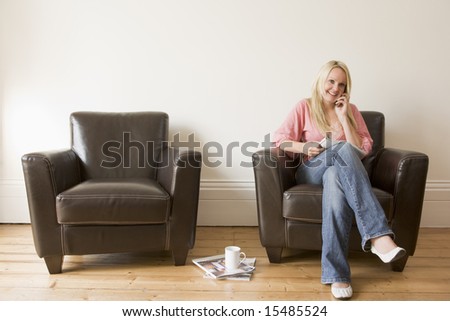 Woman sitting in chair with magazine on cellular phone smiling