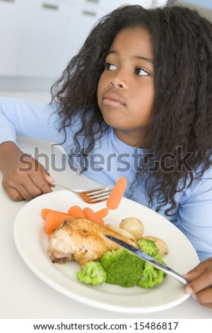 Girl eating chicken and vegetable dinner at home