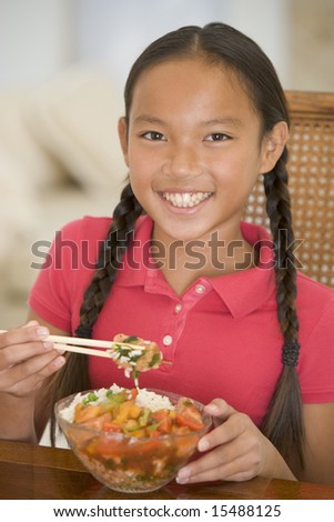 Young girl in dining room eating Chinese food smiling