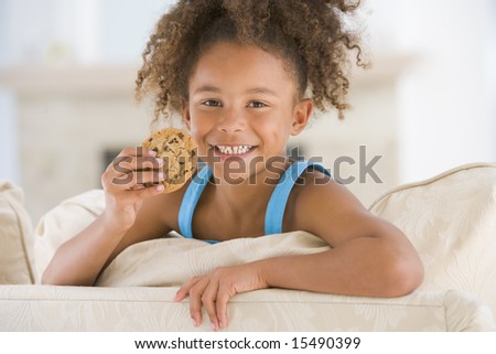 Young girl eating cookie in living room smiling