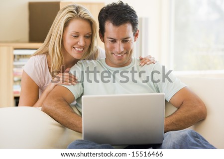 Couple in living room using laptop smiling