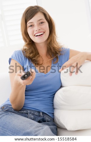 Woman in living room with remote control smiling