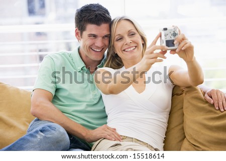 Couple in living room with digital camera smiling