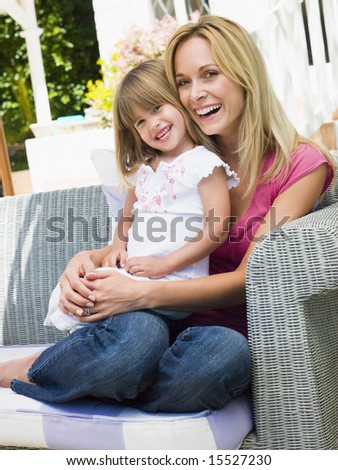 Woman and young girl sitting on patio laughing