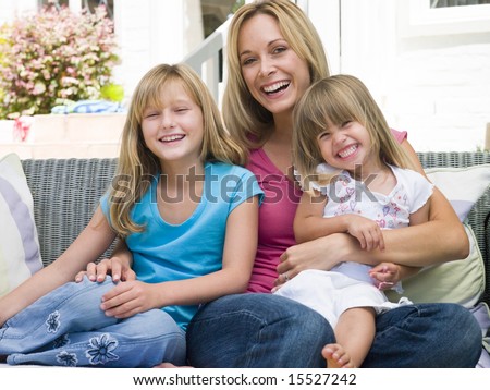 Woman and two young girls sitting on patio smiling