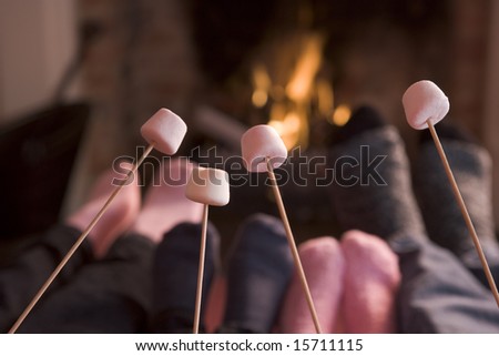 Feet warming at a fireplace with marshmallows on sticks