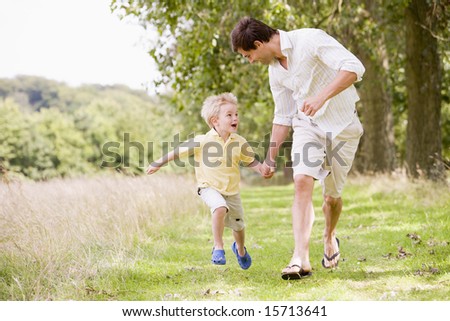 Father and son running on path holding hands smiling