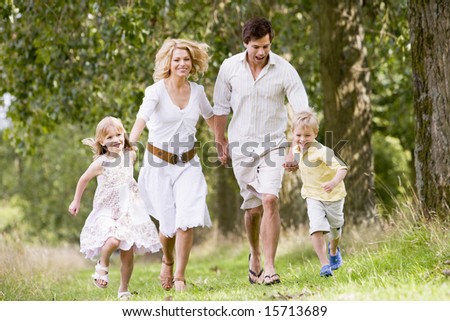 Family running on path holding hands smiling - stock photo