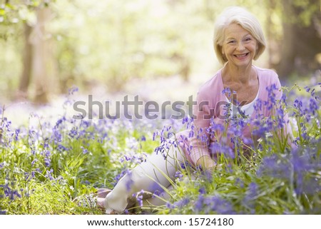 Woman sitting outdoors with flowers smiling