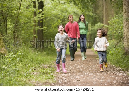 Family walking on path holding hands smiling - stock photo
