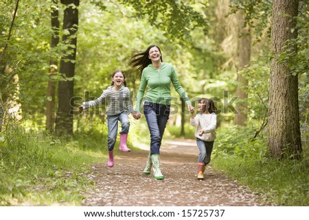 Mother and daughters skipping on path smiling
