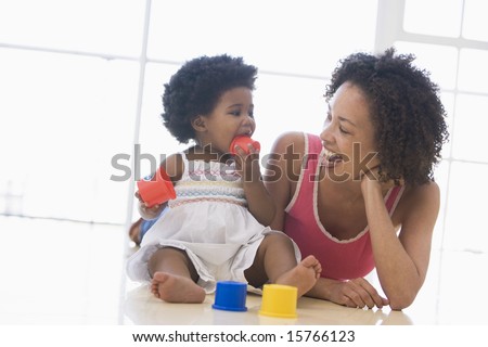 Mother and daughter indoors kissing and smiling