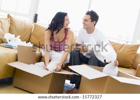 Couple unpacking boxes in new home smiling