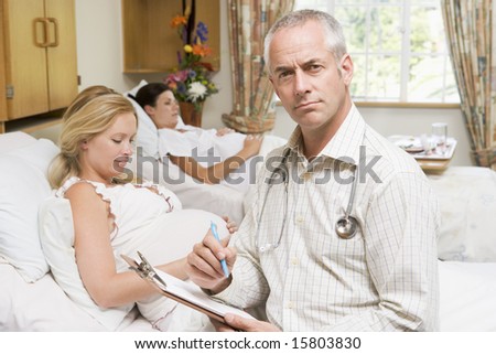 Doctor sitting by pregnant women holding chart and smiling