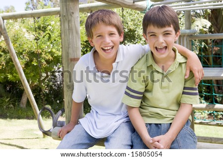 Two young male friends at a playground smiling