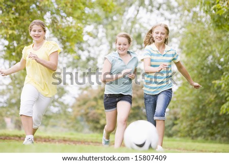 Three young girl friends playing soccer