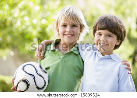 Two young boys outdoors with soccer ball smiling Two young boys outdoors with soccer ball smiling