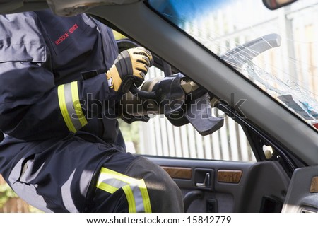 Firefighters breaking a car windscreen to help a car crash victim