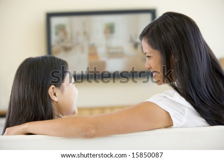 Woman and young girl in living room with flat screen television smiling