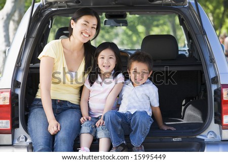 Woman with two children sitting in back of van smiling