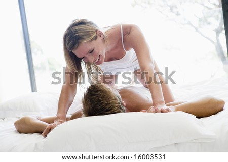Couple lying in bed being playful and smiling