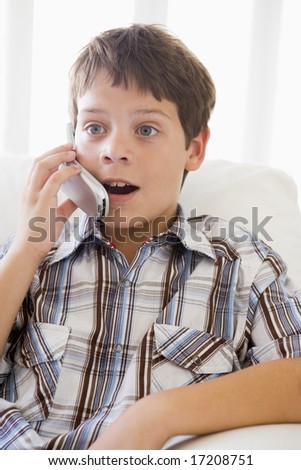 Young Boy Sitting On A Sofa Talking On A Mobile Phone