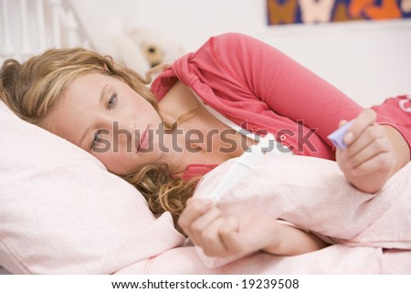 Teenage Girl Lying In Bed Looking At A Pregnancy Test