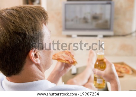 Man Enjoying Beer And Pizza In Front Of TV