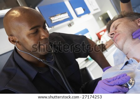 Paramedic listening to patients heartbeat