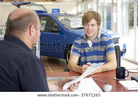 Young man filling in paperwork in car showroom