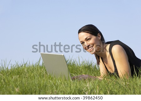 Woman Using Laptop Outdoors In Summer Countryside