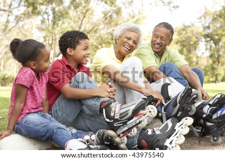 Grandparent With Grandchildren Putting On In Line Skates In Park