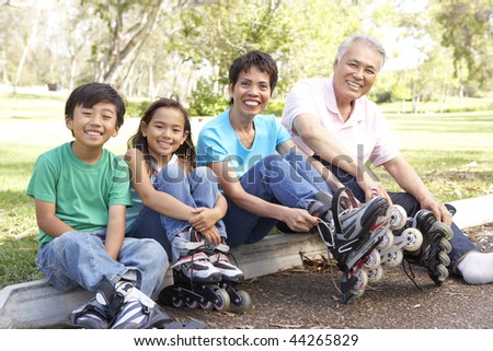 Grandparents With Grandchildren Putting On In Line Skates In Park
