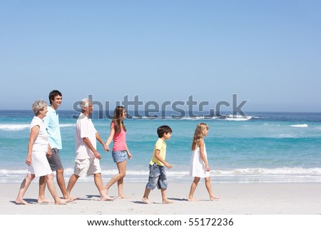 Three Generation Family Walking Along Sandy Beach
