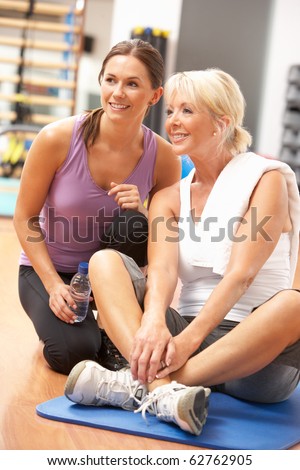 Woman Doing Stretching Exercises In Gym With Trainer
