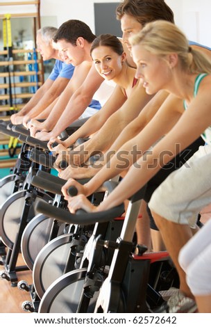 Senior Woman Cycling In Class In Gym