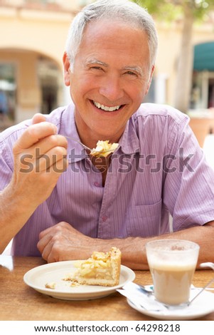 Senior Man Enjoying Coffee And Cake In Cafe