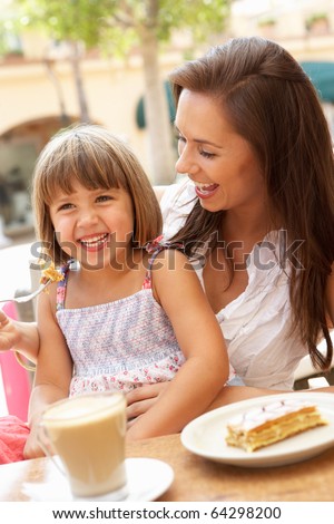 Mother And Daughter Enjoying Cup Of Coffee And Piece Of Cake In Cafe