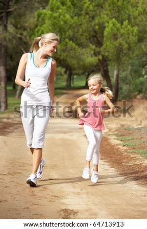 Mother and daughter running in park