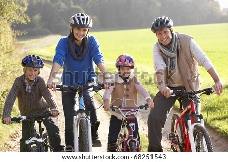 Young family pose with  bikes in park