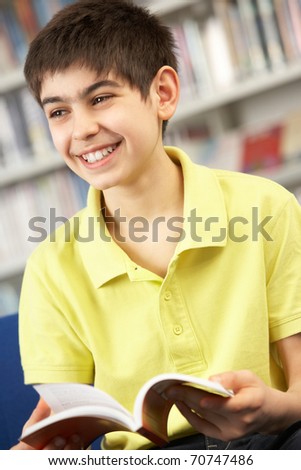 Male Teenage Student In Library Reading Book