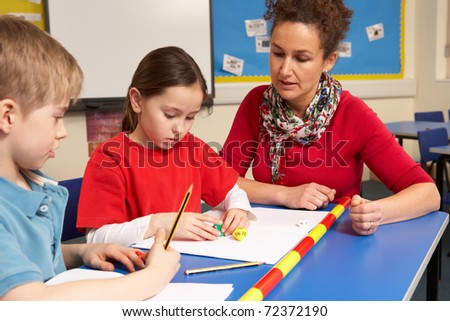Schoolgirl And Schoolboy Studying In Classroom With Teacher