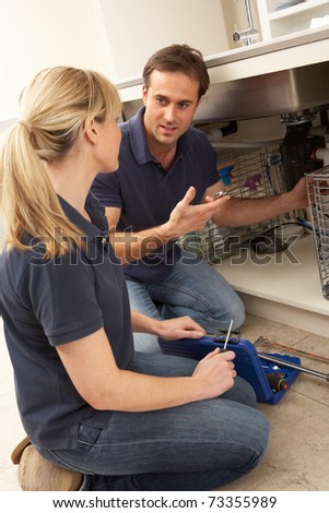 Plumber Teaching Apprentice To Fix Kitchen Sink In Home