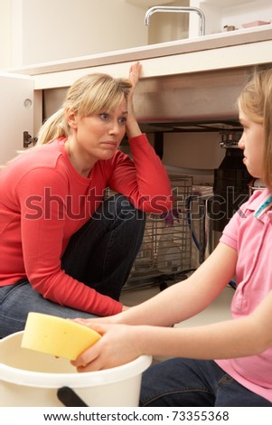 Daughter Helping Mother To Mop Up Leaking Sink