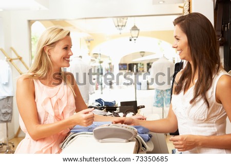 Female Sales Assistant At Checkout Of Clothing Store With Customer